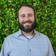 A lush green background with a smiling man in casu.  Gxmble Casino Online